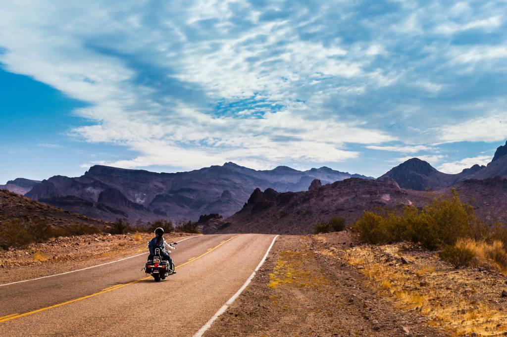 Photo d'une route déserte en Californie avec un motard qui roule seul, parue dans les Boomeurs